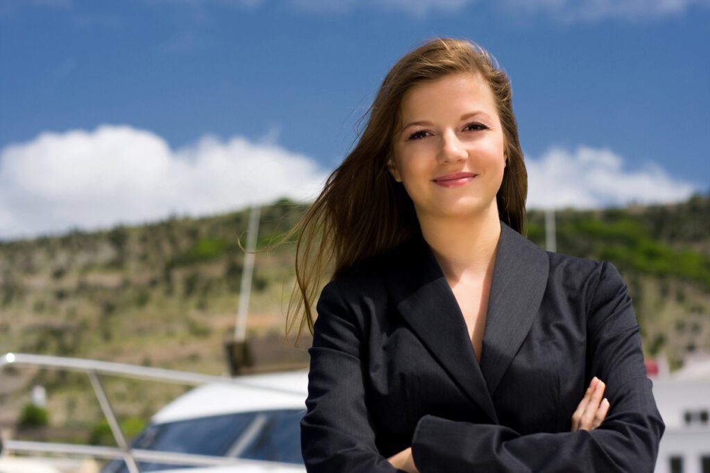 Professional travel representative standing confidently near marina with scenic background